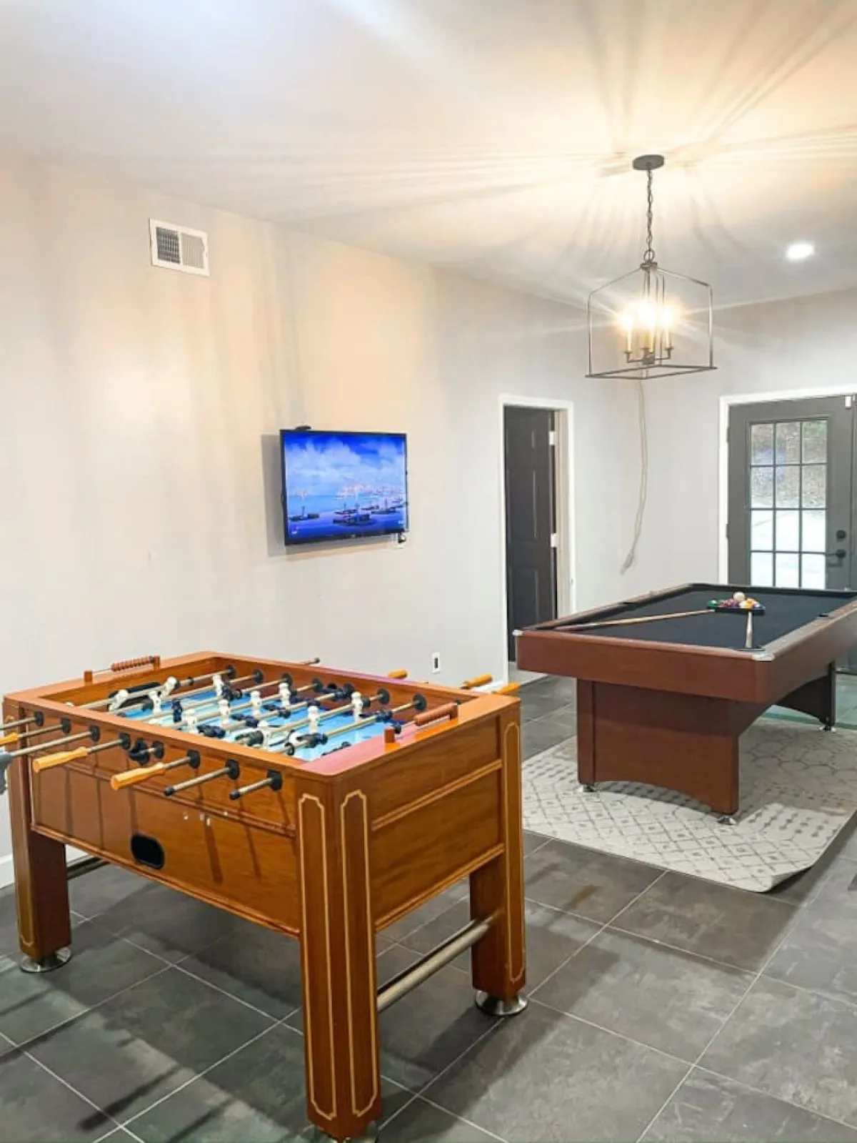 This image captures a vibrant interior game room featuring a foosball table, pool table, and a television. The space is clearly designed for recreational fun and social gatherings, perfect for hosting game nights or friendly competitions.