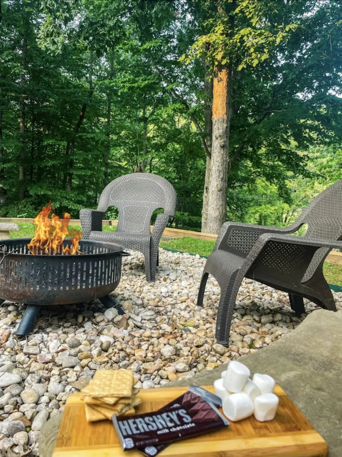A cozy outdoor fire pit area with lawn chairs and a snack tray set in a tranquil yard. The space invites guests to gather around the fire, enjoy snacks, and share stories under the stars, perfectly matching the communal, celebratory vibe of group getaways.