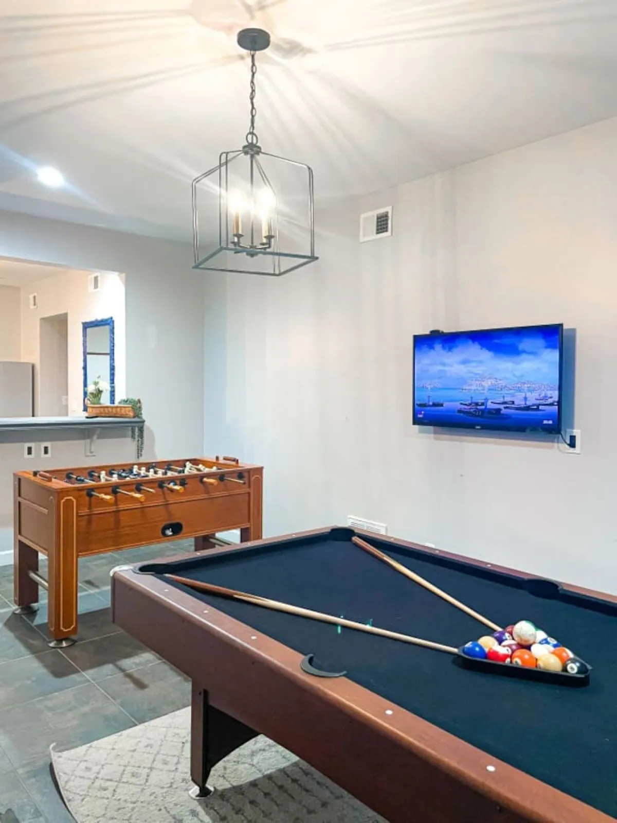 This lively interior shot features a pool table and foosball table under a chandelier, with a TV screen nearby—evoking the excitement of friendly competitions and socializing. The space is designed for interactive group entertainment, making it ideal for game nights or casual get-togethers.